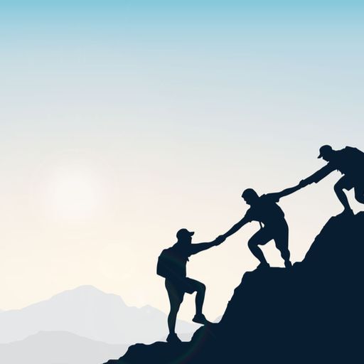 a man is helping another man climb a mountain .
