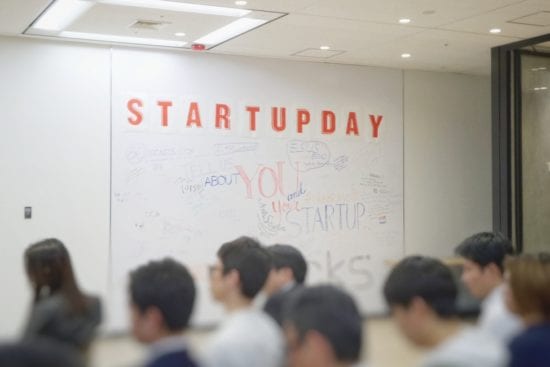 a group of people are standing in front of a whiteboard .