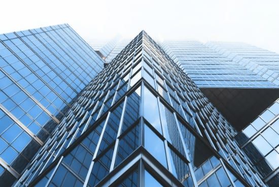 looking up at a tall building with a lot of windows on a white background .