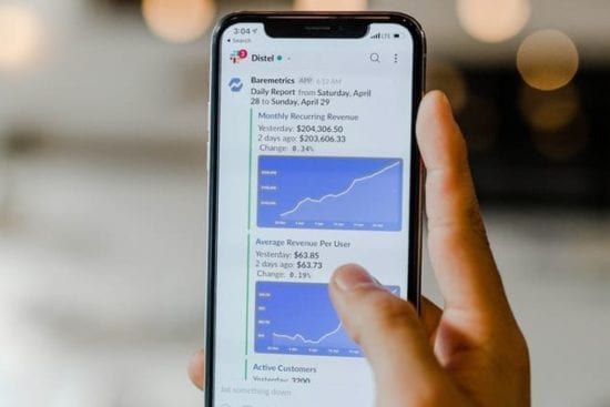 a person is holding a cell phone with a graph on the screen .