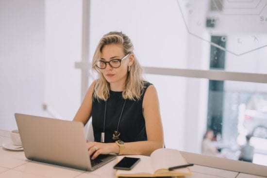 a woman is sitting at a table using a laptop computer .
