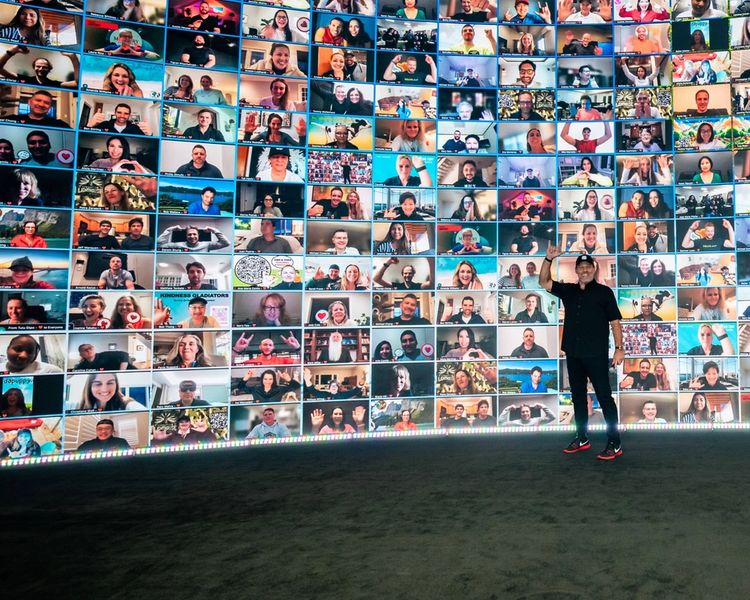 a man is standing in front of a wall filled with lots of pictures of people .