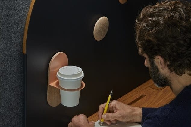 a man is writing on a piece of paper next to a coffee cup holder .