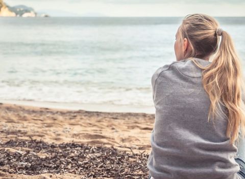 a woman is sitting on the beach looking at the ocean .