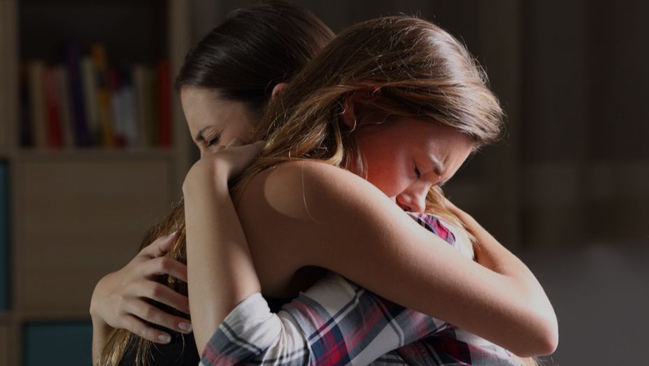 two women are hugging each other in a dark room .