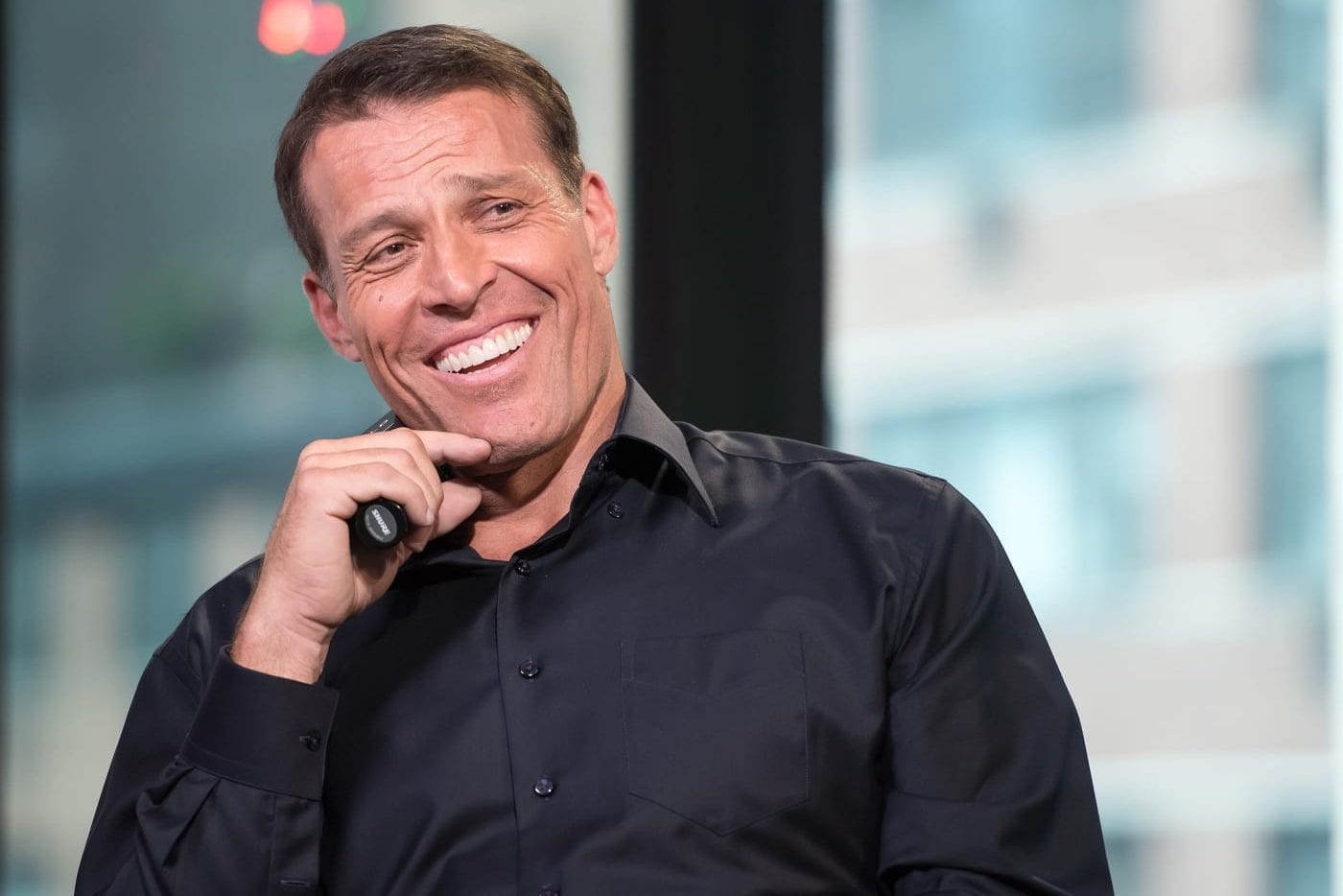 a man in a black shirt is smiling while holding a microphone .