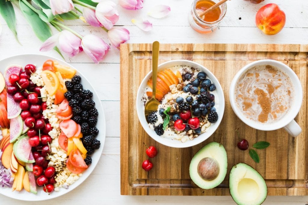 a wooden cutting board topped with bowls of food and fruit .