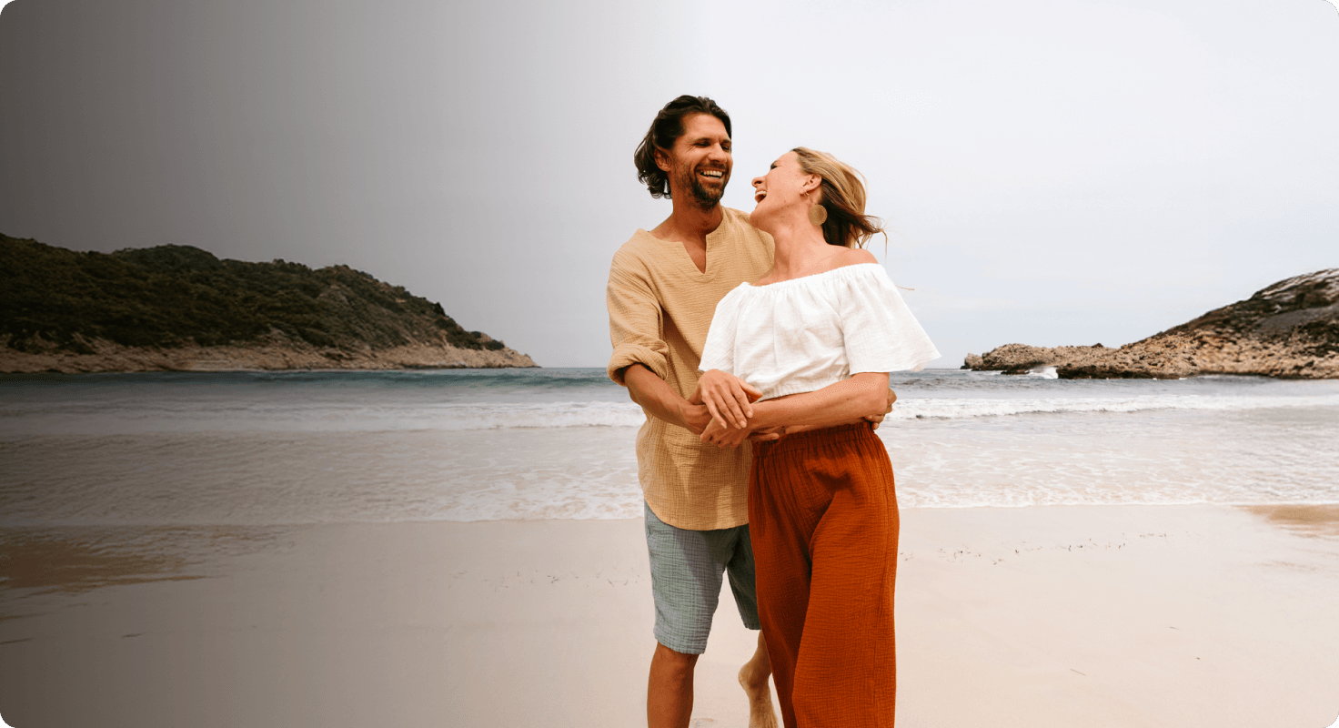 a man and a woman are laughing on the beach