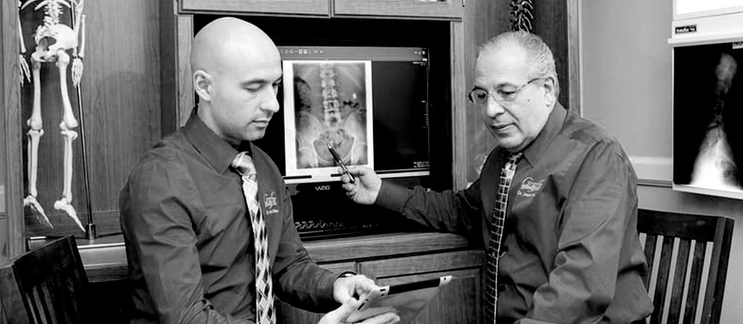 two men are looking at an x-ray together in a black and white photo .