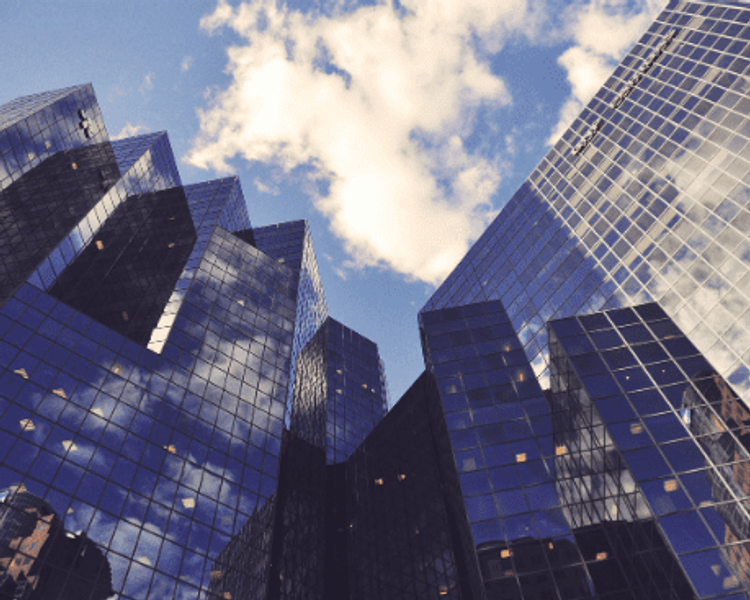 looking up at a row of skyscrapers with a blue sky in the background