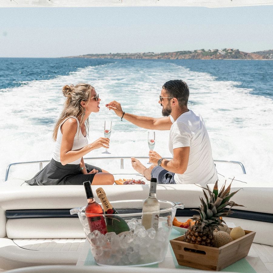 a man and a woman are drinking wine on a boat in the ocean .