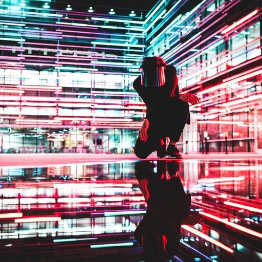 a person is kneeling down in front of a building with neon lights .