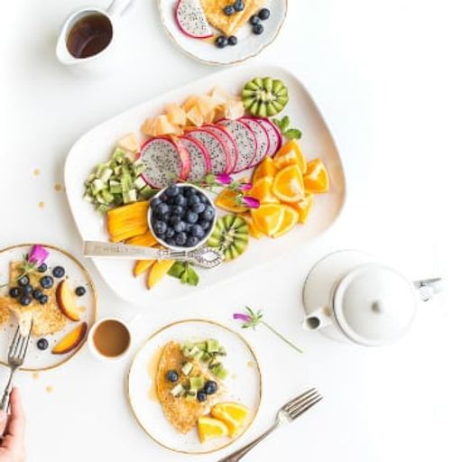 a person is sitting at a table eating a plate of fruit .