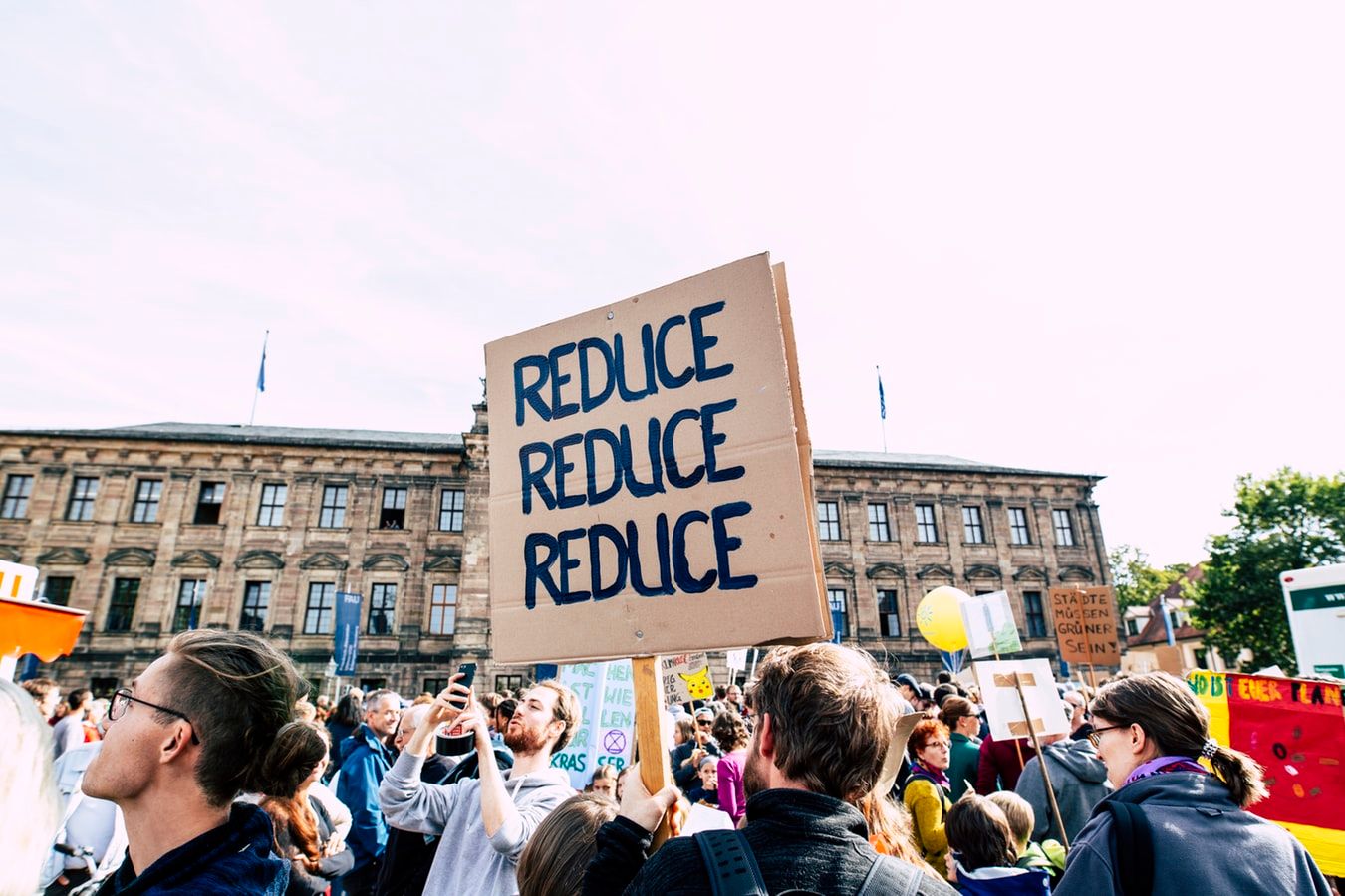 a group of people are holding a sign that says `` reduce reduce reduce '' .