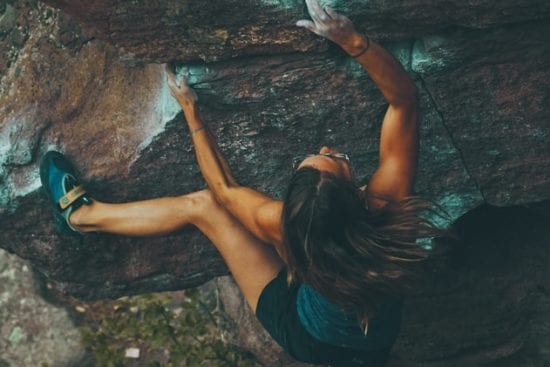 a woman is climbing up a rock wall .