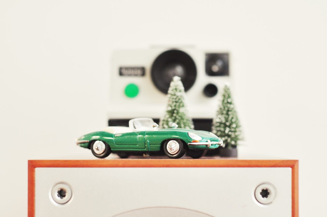 a green toy car is sitting on top of a speaker .