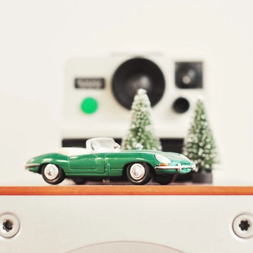 a green toy car is sitting on top of a speaker .