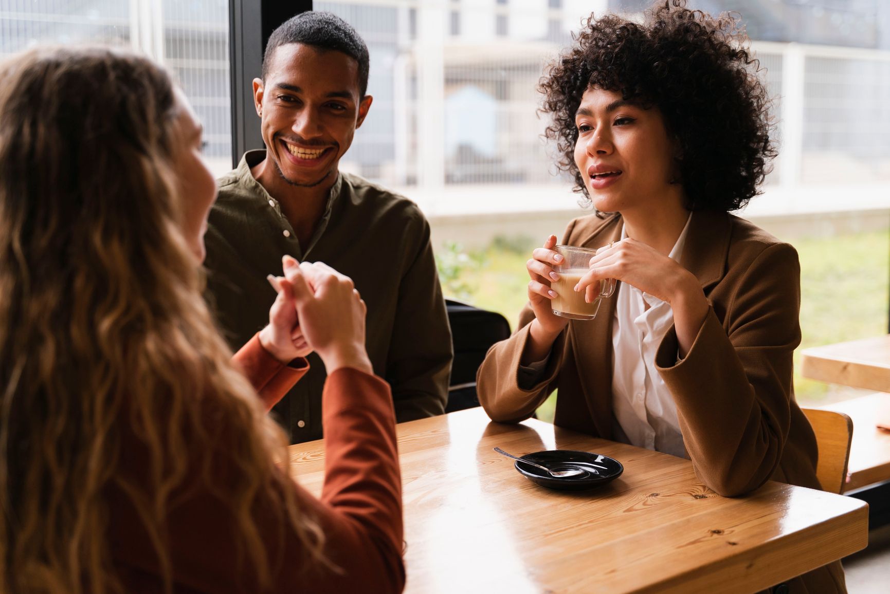 a group of people are sitting at a table drinking coffee and talking .