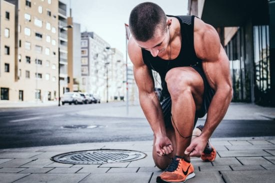 a man is tying his shoes on the sidewalk .