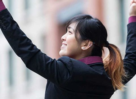 a woman in a suit is raising her arms in the air .