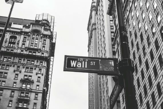 a black and white photo of a wall street sign in front of a building .
