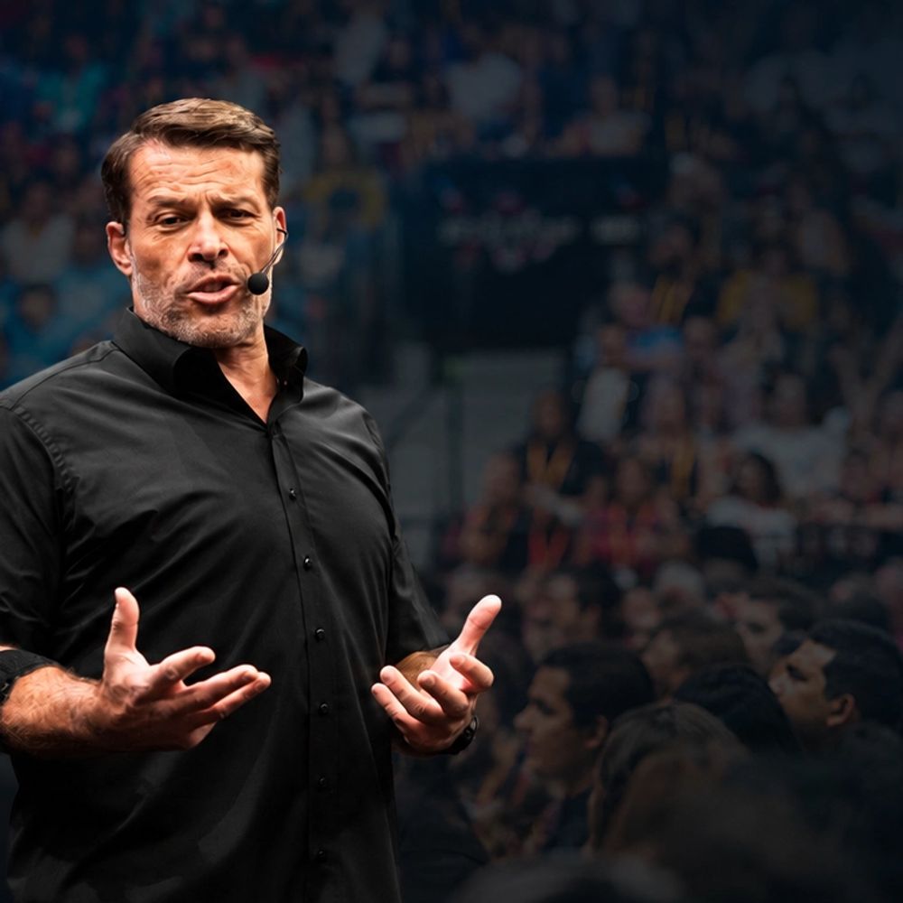 Tony Robbins speaking on stage to a large audience.