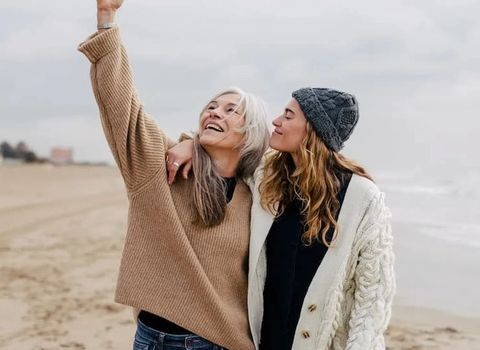 two women are standing next to each other on the beach .