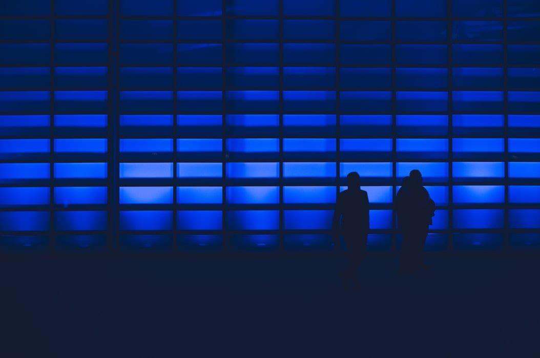 two people are standing in front of a blue wall .