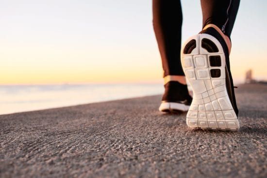 a person is walking on a sidewalk near the ocean .
