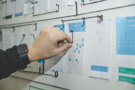 a person is pinning a piece of paper to a whiteboard .