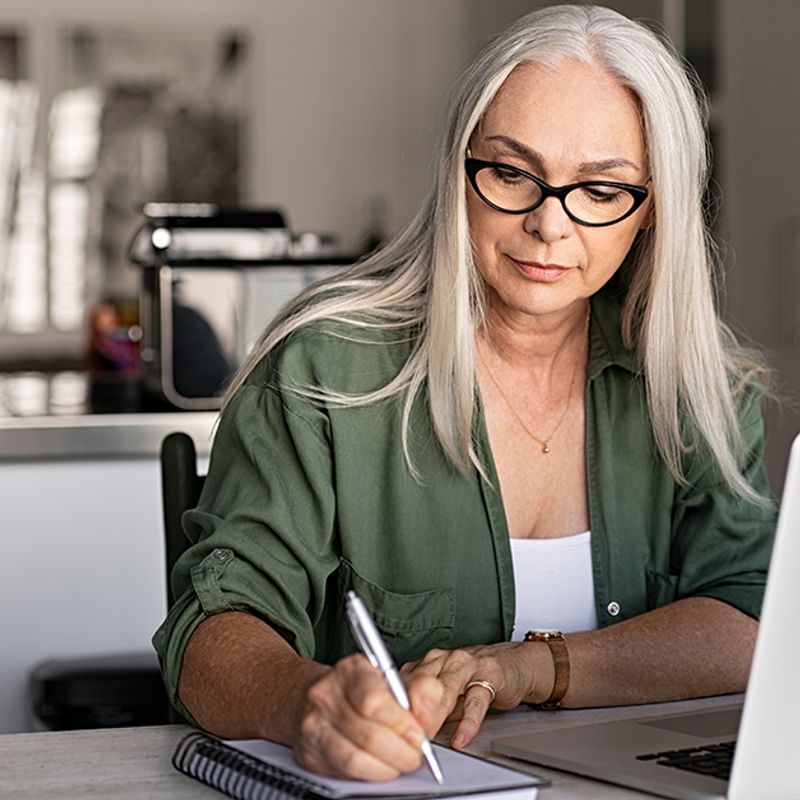How to protect your business image of older woman writing notes in front of a laptop