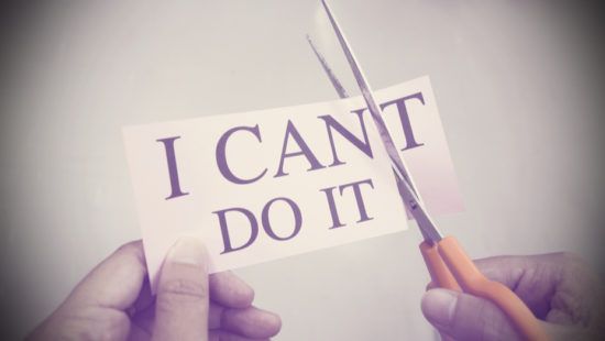 a person is cutting a piece of paper that says `` i can t do it '' with scissors .
