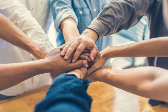 a group of people are putting their hands together in a circle .