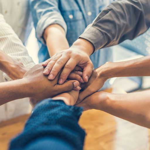 a group of people are putting their hands together in a circle .