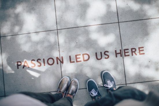 a couple of people standing on a tiled floor with the words `` passion led us here '' written on it .