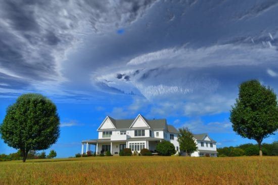a large white house is sitting on top of a grassy hill .