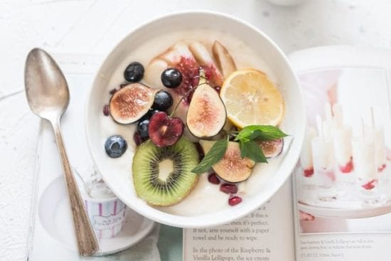 a bowl of yogurt with fruit and a spoon on a table .