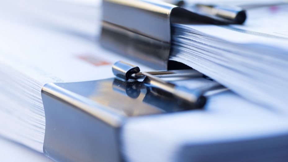 a close up of a stack of binder clips on top of a stack of papers .