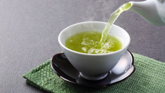 green tea is being poured into a white cup on a saucer .