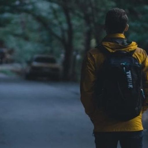 a man with a backpack is walking down a road at night .