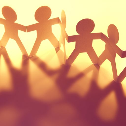 a group of paper people are holding hands in a row .