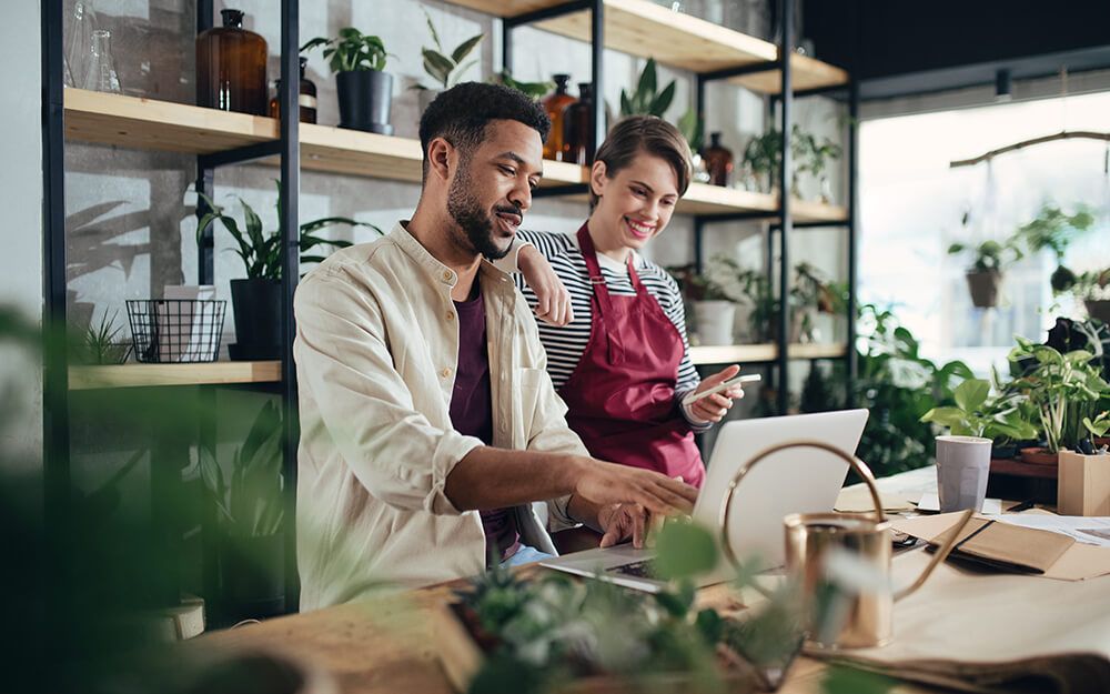 a man and a woman are looking at a laptop in a flower shop .
