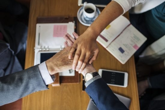 a group of people are putting their hands together on a table .