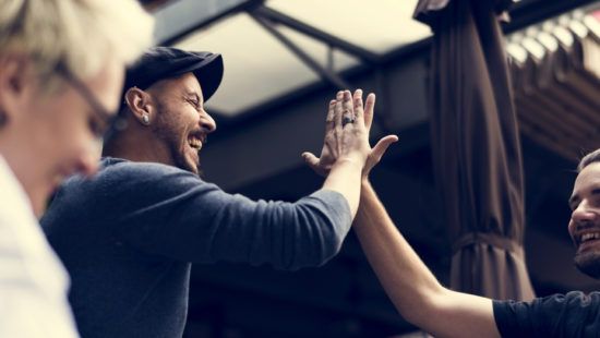 a group of men are giving each other a high five .