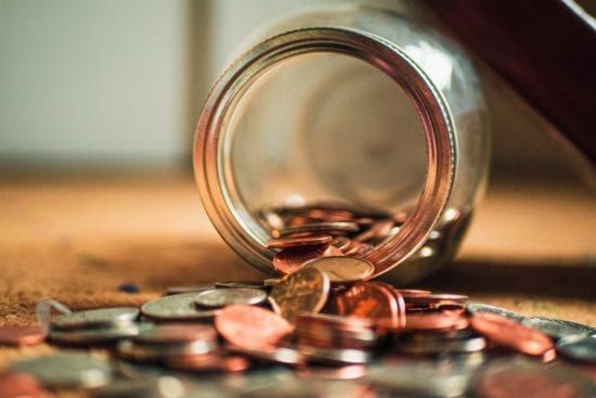 a jar filled with coins is spilling out on a table .