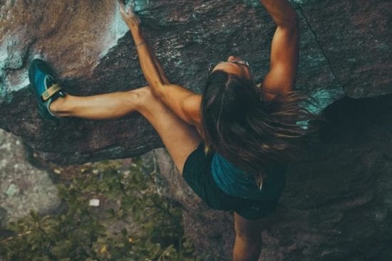 a woman is climbing up a large rock .