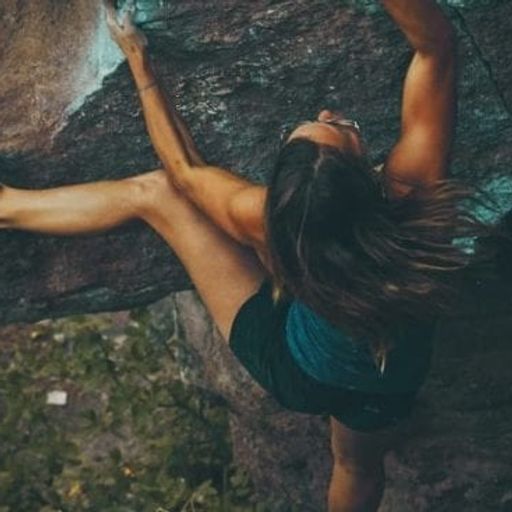 a woman is climbing up a large rock .