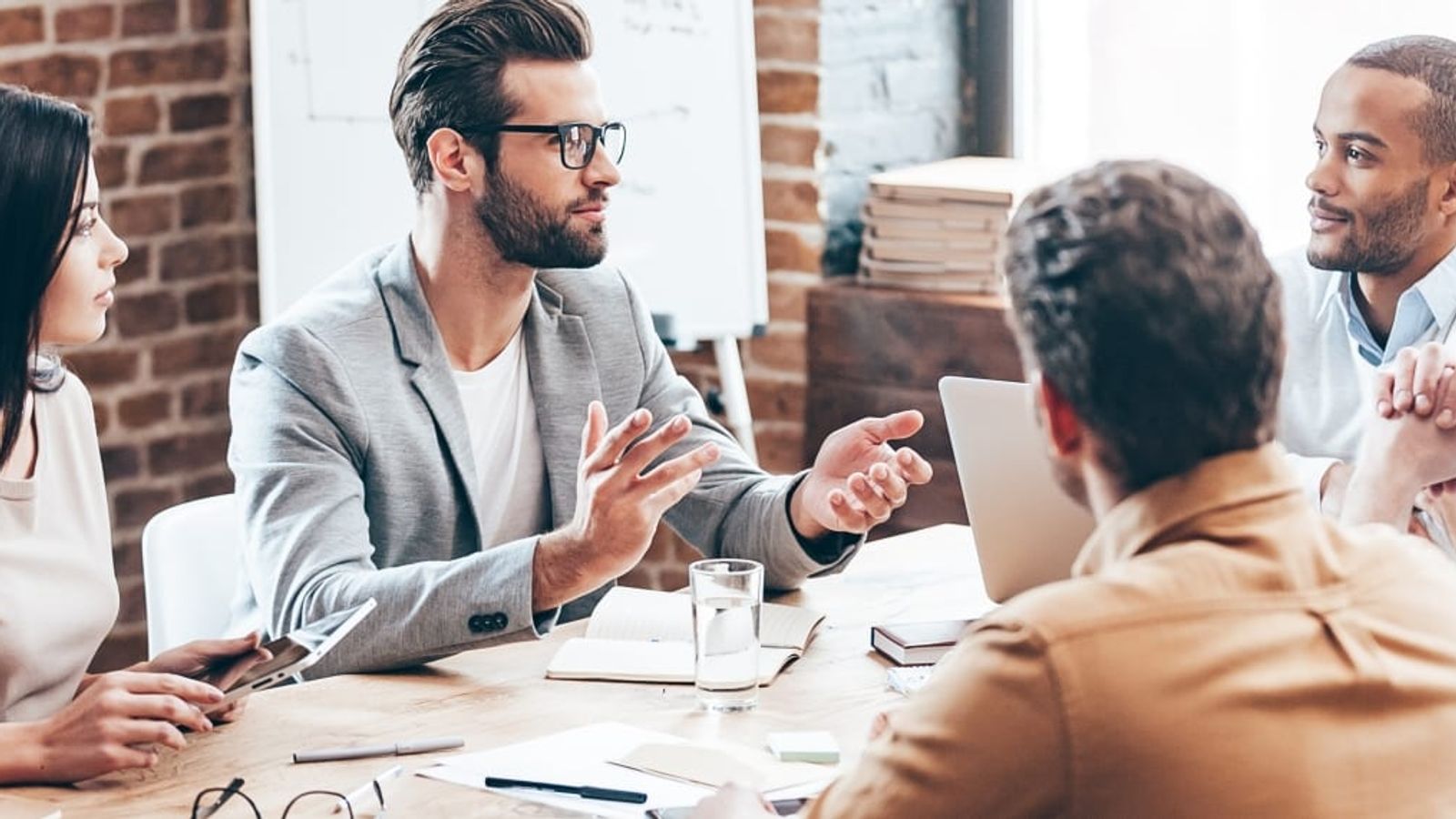 a group of people are sitting around a table having a meeting .