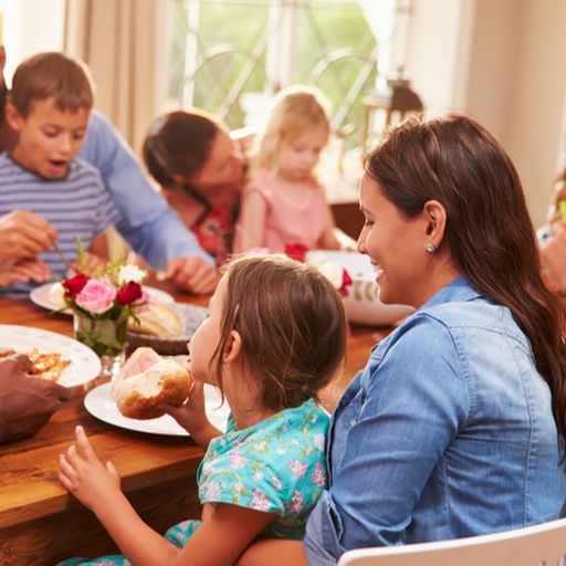 a large family is sitting at a table eating food .