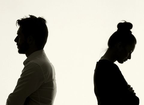 a man and a woman are standing back to back with their arms crossed .